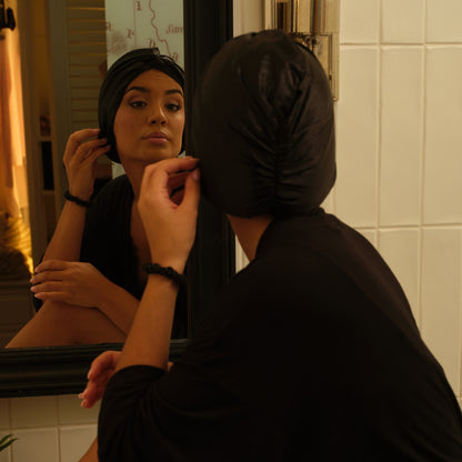 Modelo con gorro de seda negro Onisa Coté frente al espejo del tocador