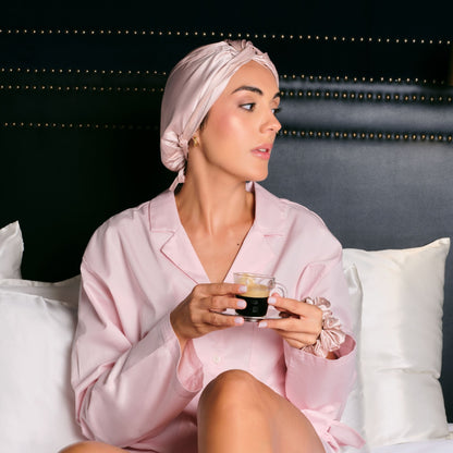 Modelo con turbante de seda rosa Onisa Coté tomando un café en la cama